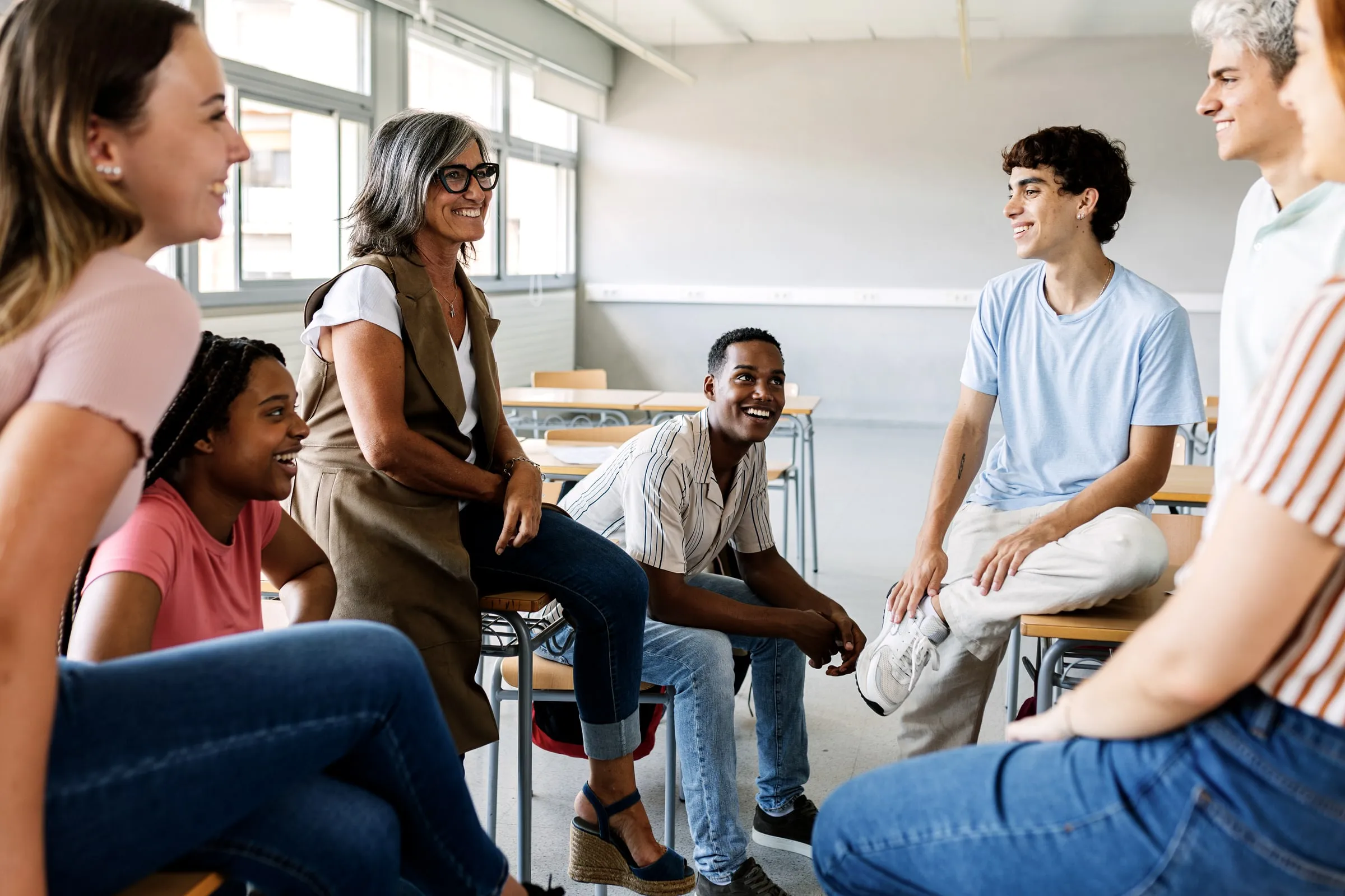 Group of adults in a bright classroom sitting and talking together