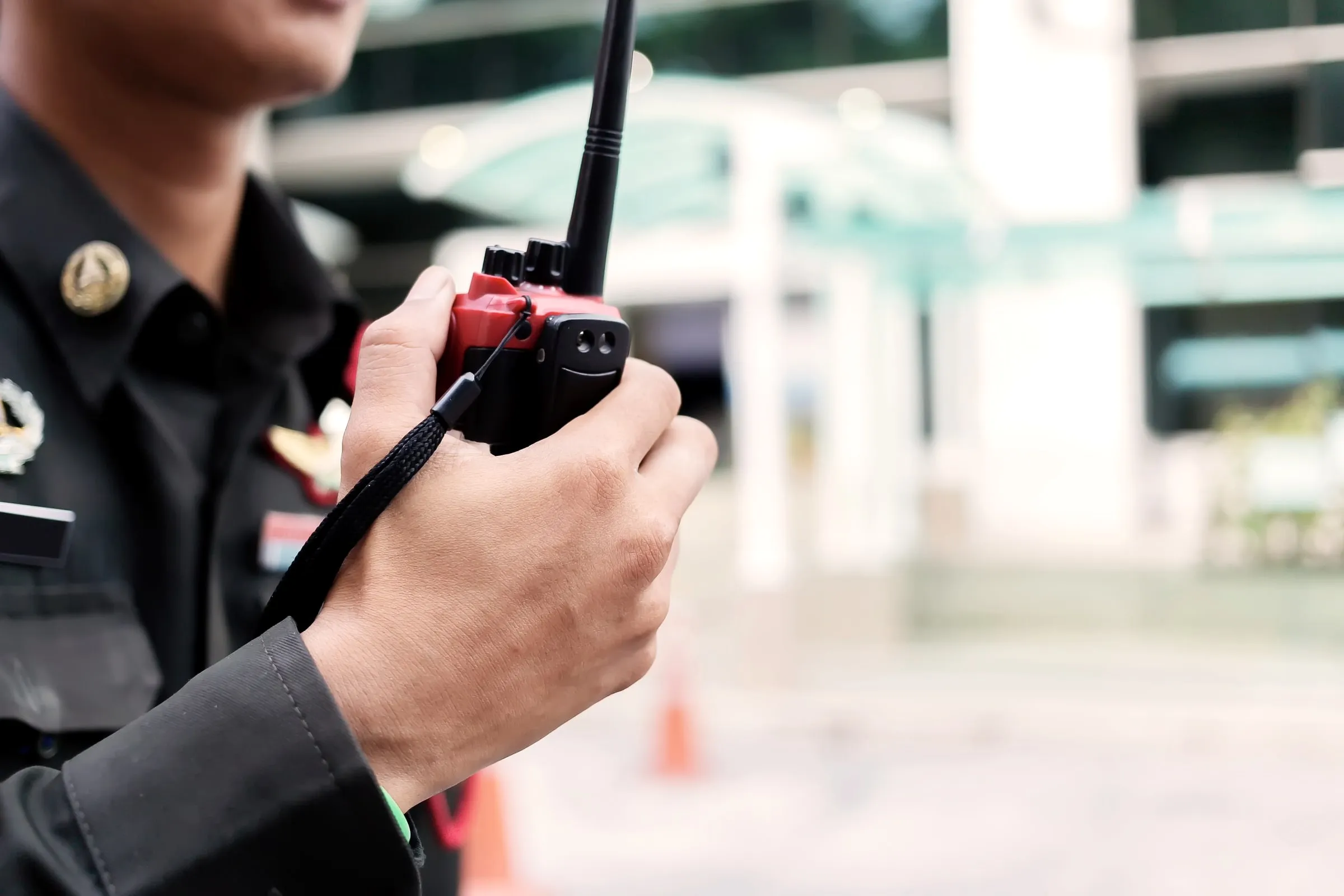Close-up of a security officer's hand holding a red-and-black handheld radio