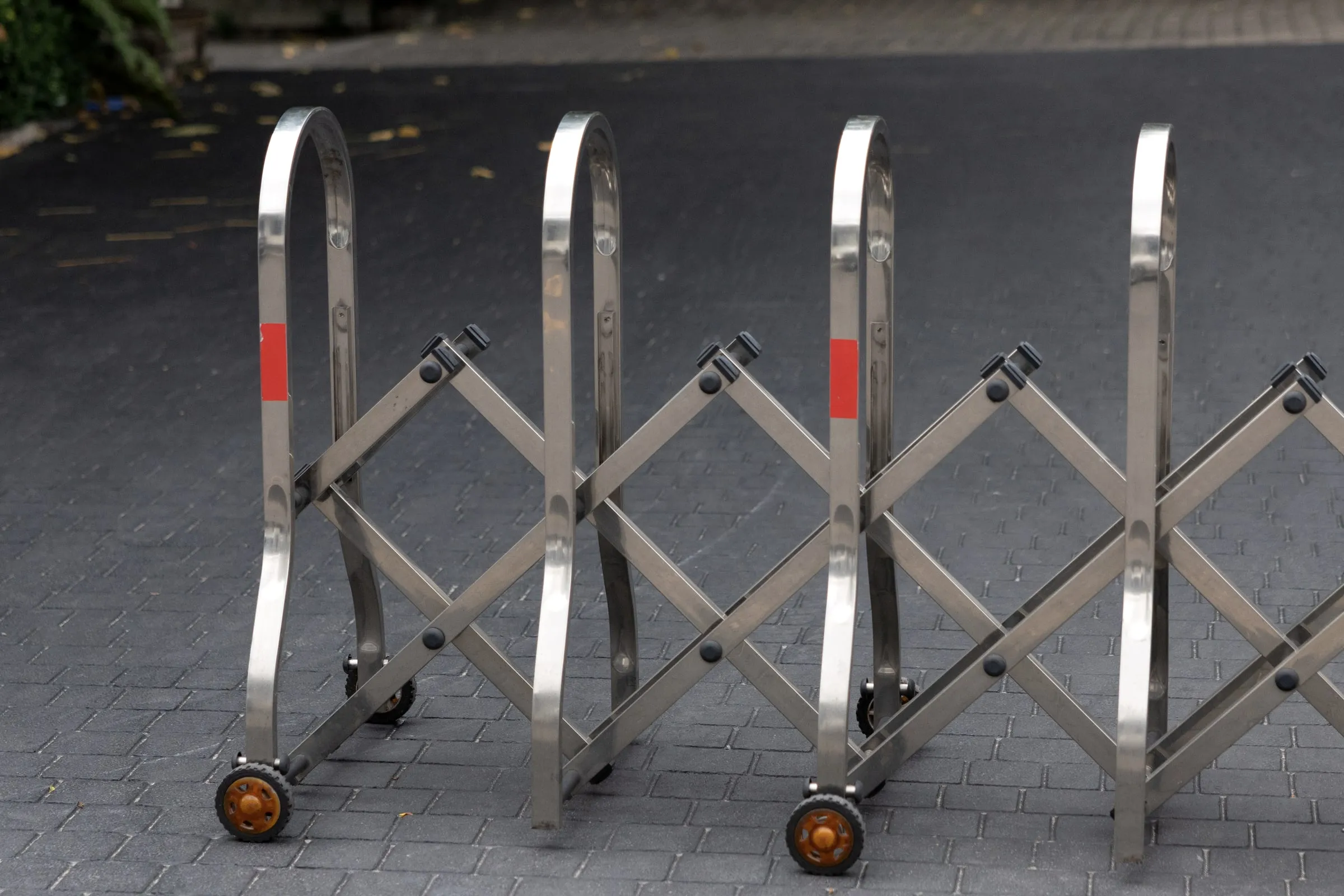 Folding steel crowd-control barriers with red stripes, stacked on wheels