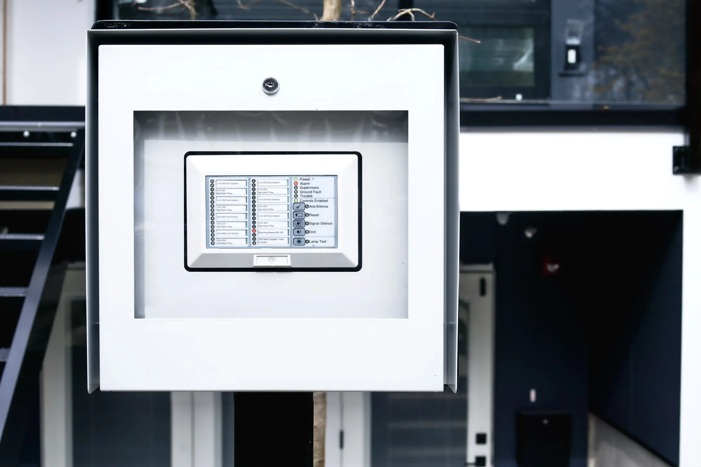 Wall-mounted key cabinet with a small screen set into a dark panel