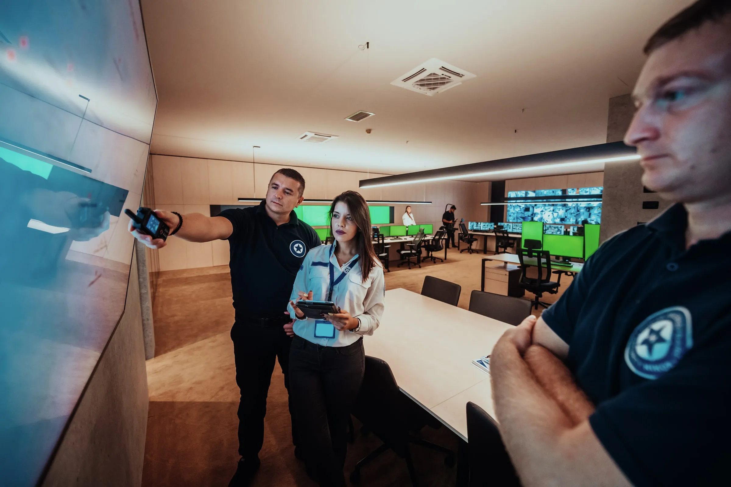 Two officers in dark uniforms in a training room, one pointing at a screen while the other holds a tablet