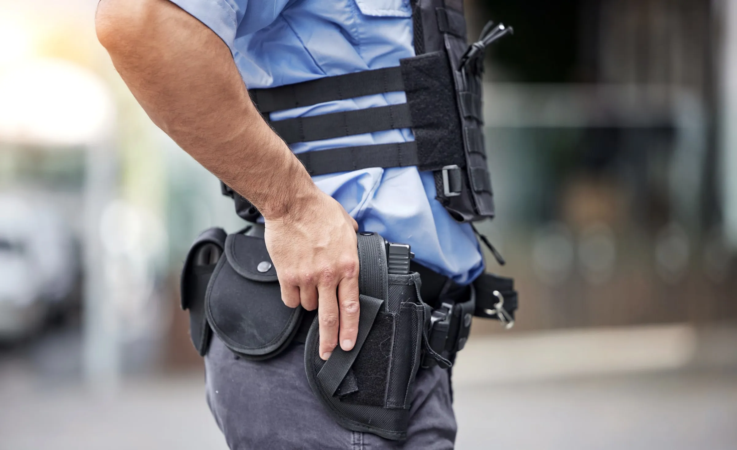 Close-up of a holstered sidearm and tactical vest on an armed security officer
