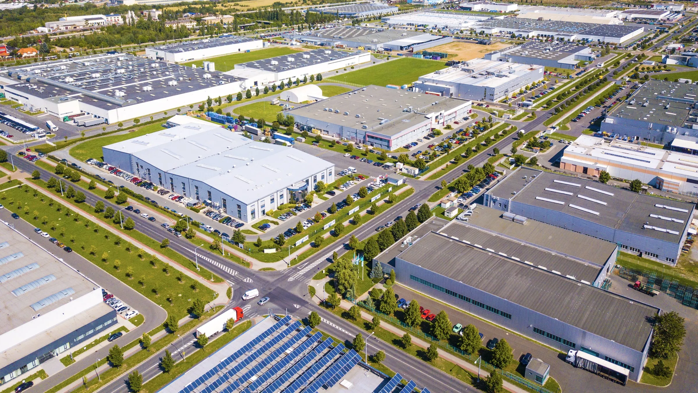 Aerial view of a multi-tenant industrial park with rows of warehouse buildings, loading docks, parked trucks and shared access roads