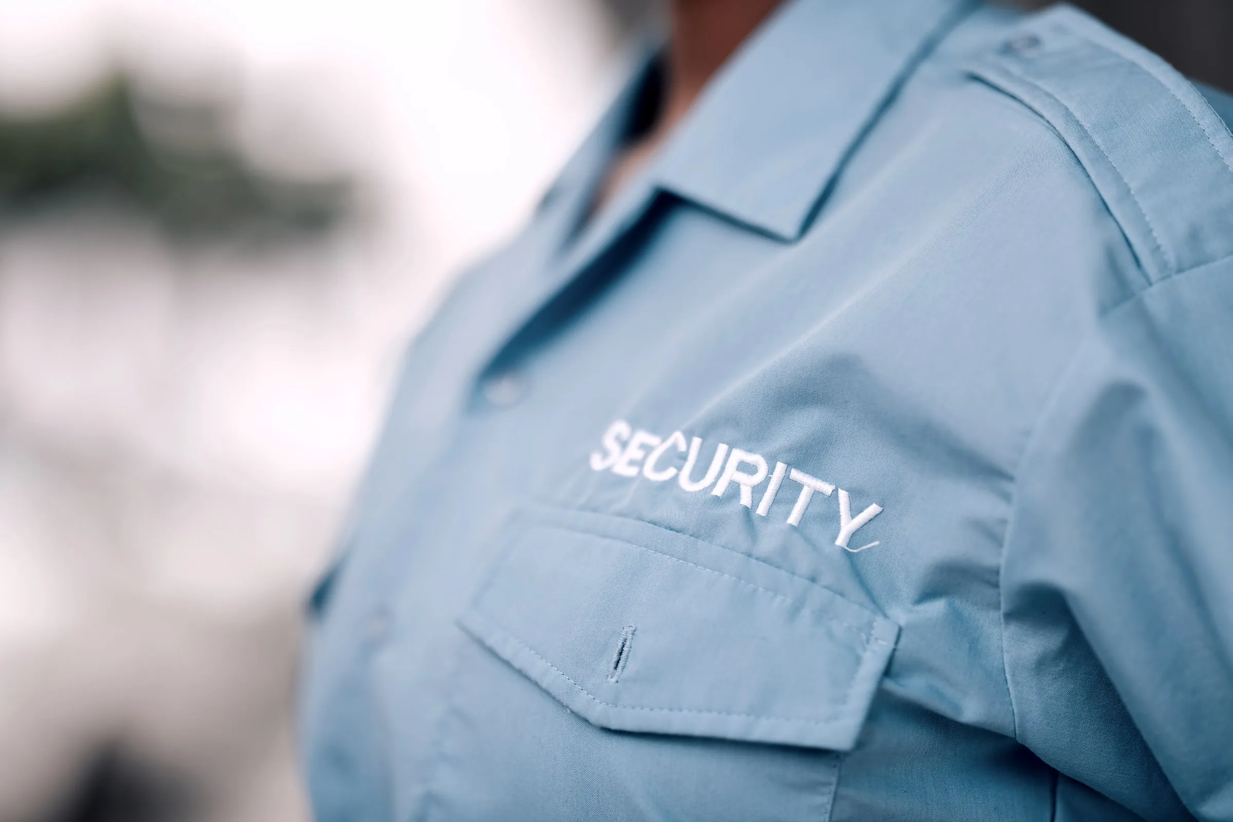 Close view of a light blue uniform shirt with SECURITY lettering across the chest
