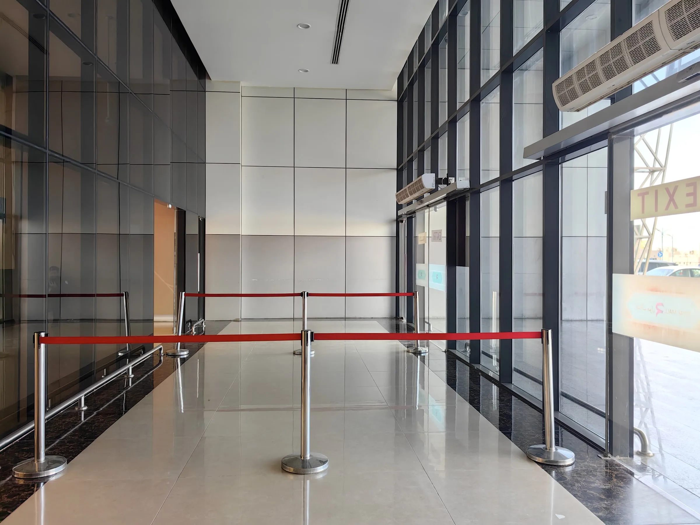 Red rope barrier on chrome stanchions across a glass-walled lobby