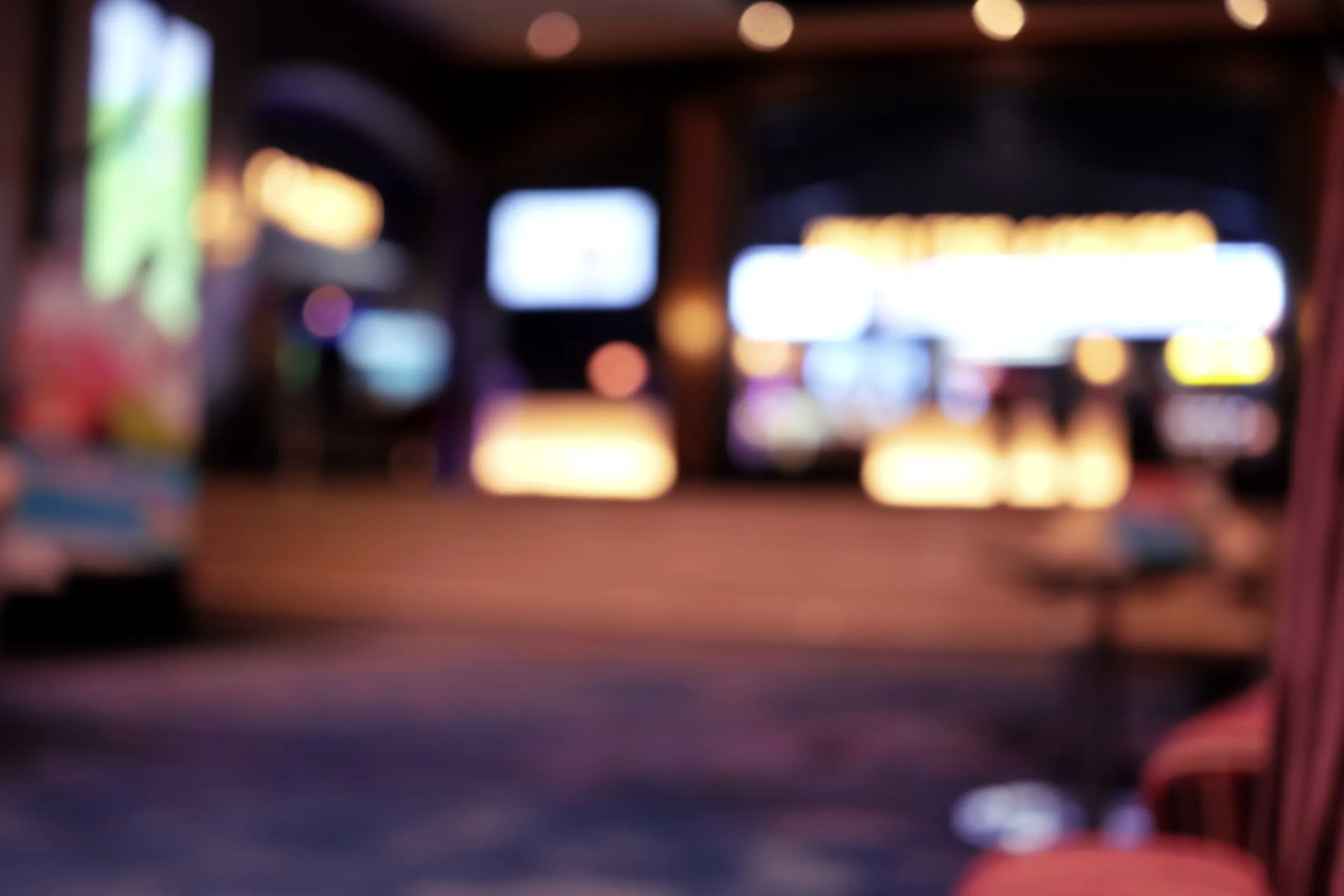 Blurred view of a theater lobby with glowing displays and a ticket counter