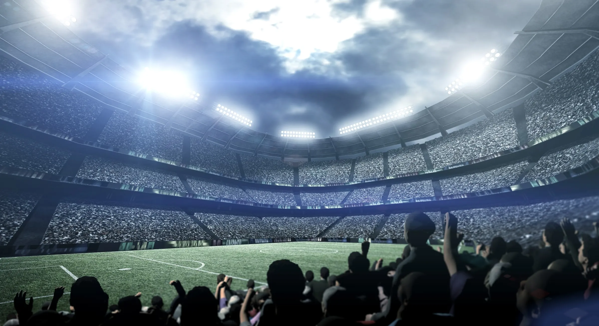 Floodlit stadium full of spectators around a green field at night