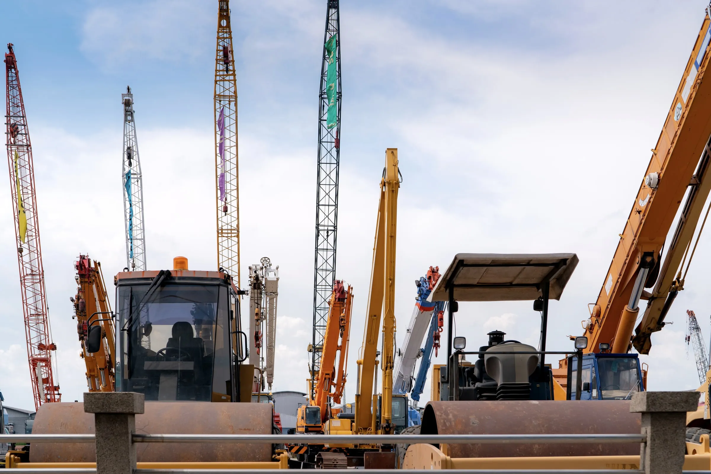 Rental yard lot crowded with parked cranes, excavators, rollers and other heavy construction equipment