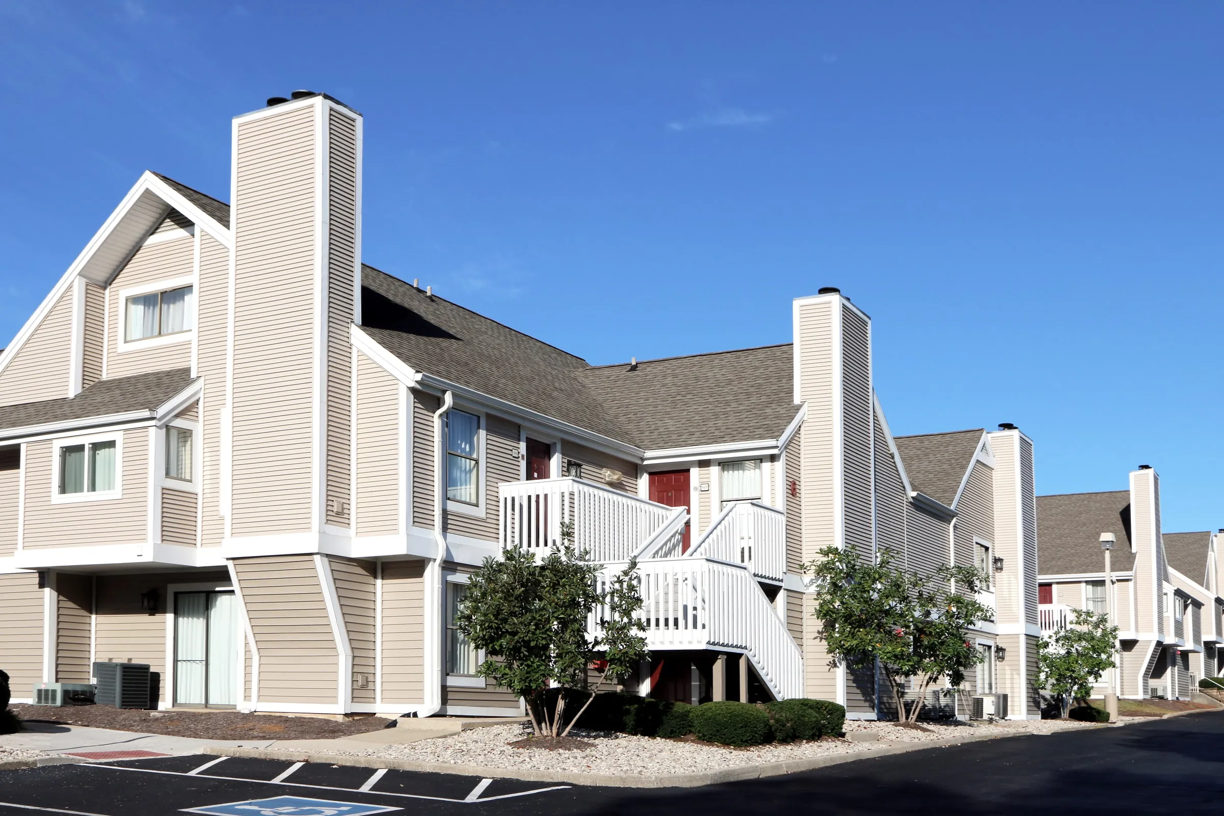 Grey two-story apartment buildings with white trim, exterior stairs and a parking lot