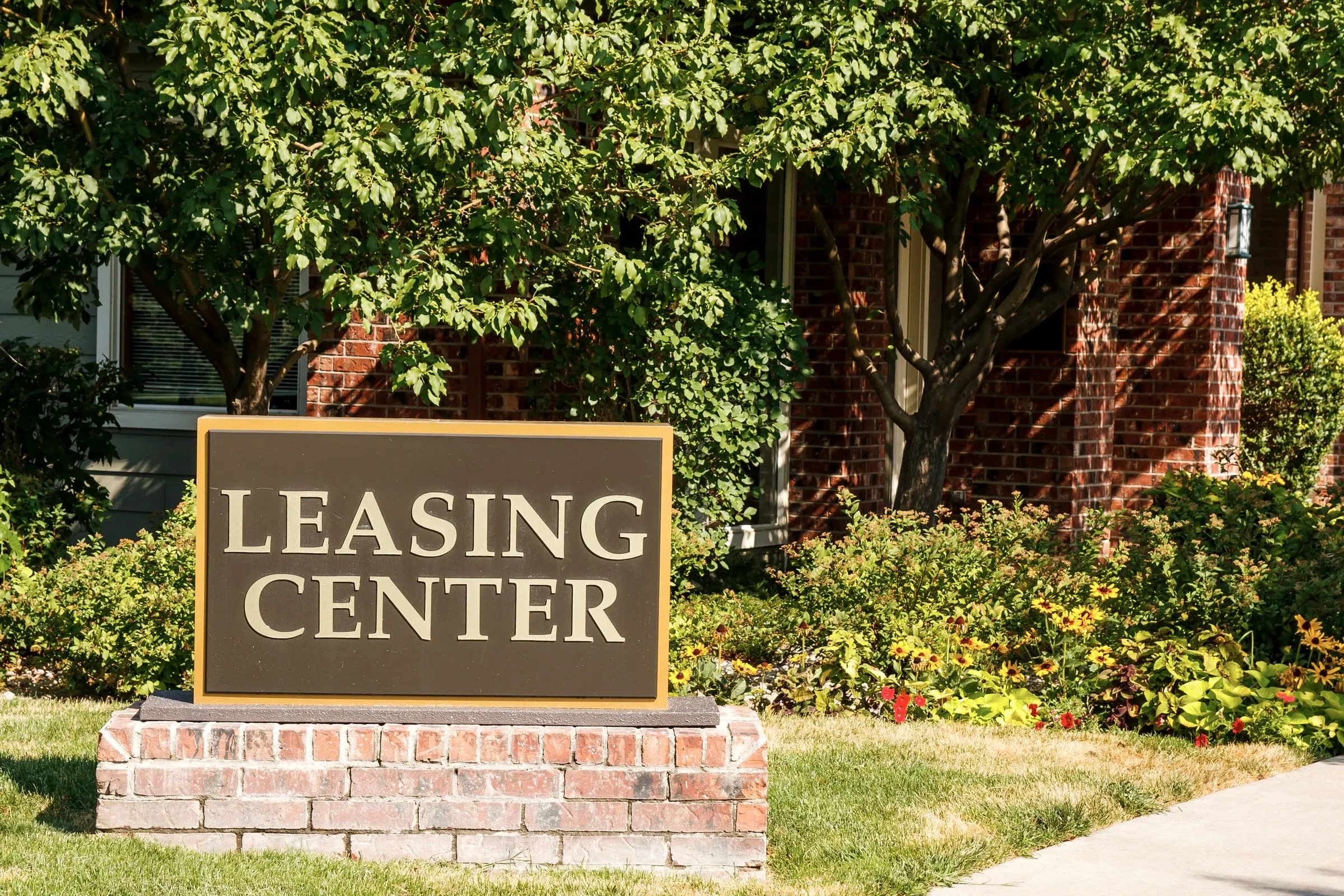 Brick monument sign reading LEASING CENTER in front of an apartment community
