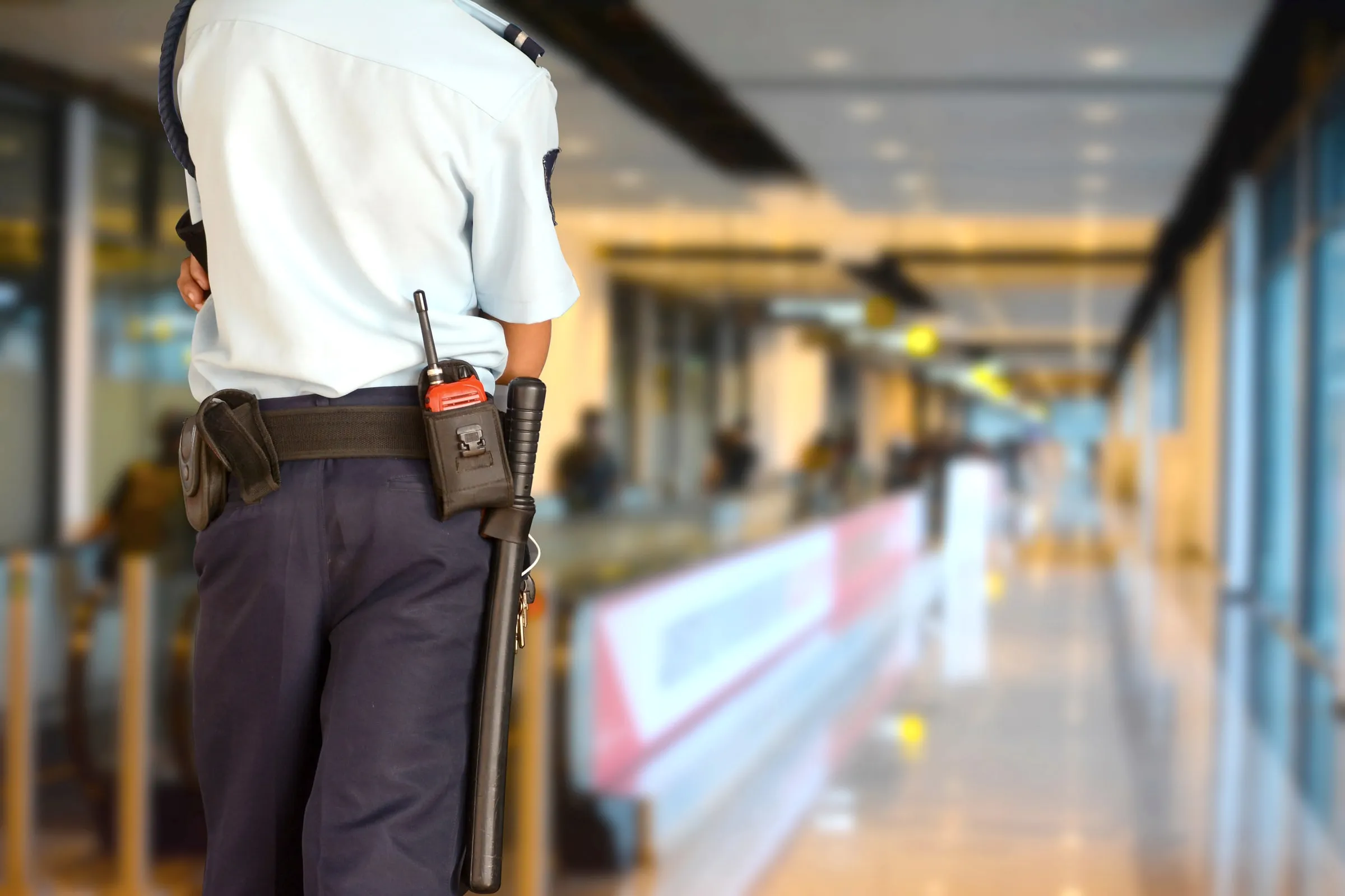 Security officer with a duty belt standing in a bright, blurred hallway