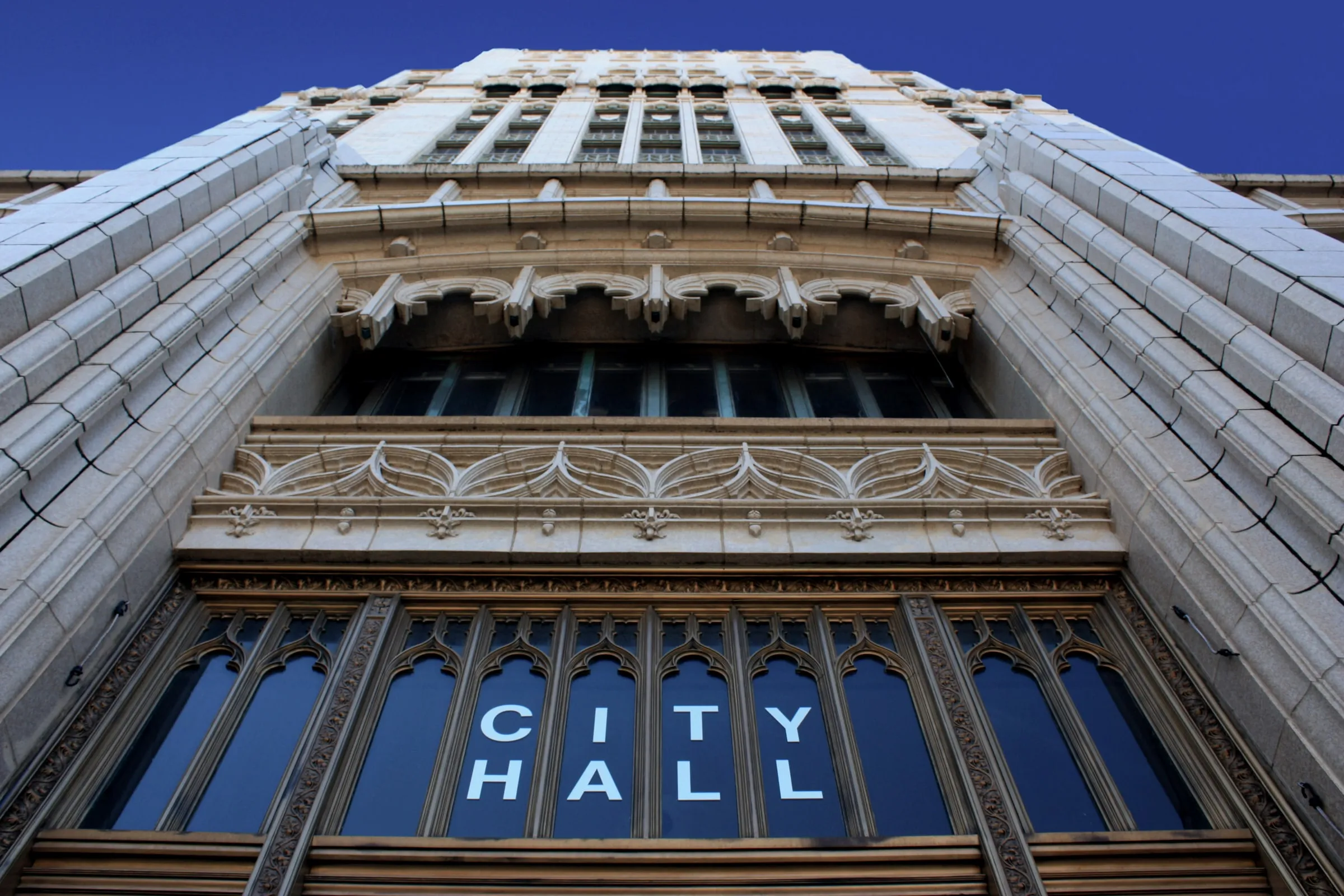 Looking up at an ornate city hall facade with CITY HALL lettering over the entrance