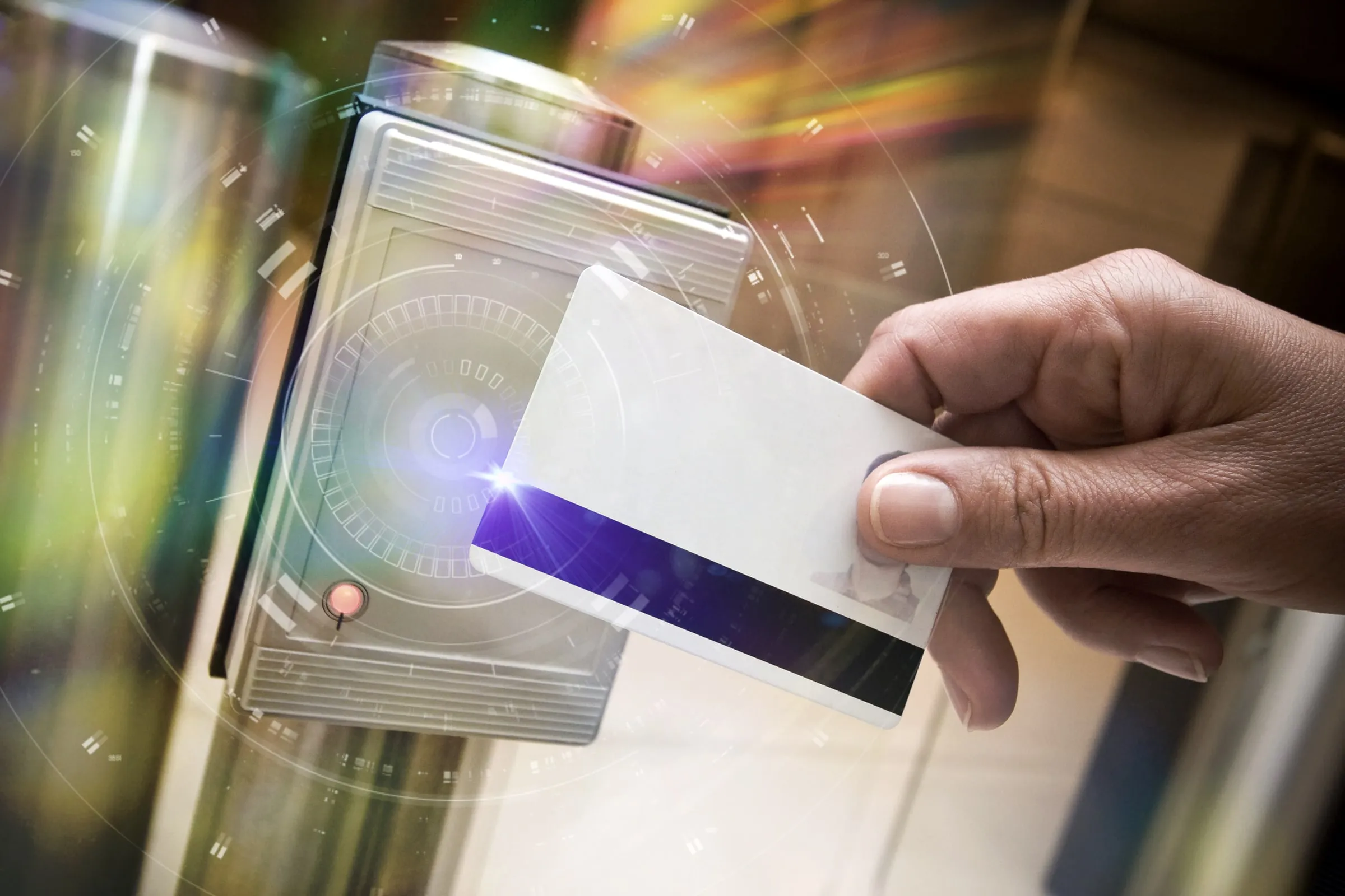 Hand holding a key card up to an electronic reader with a glowing ring