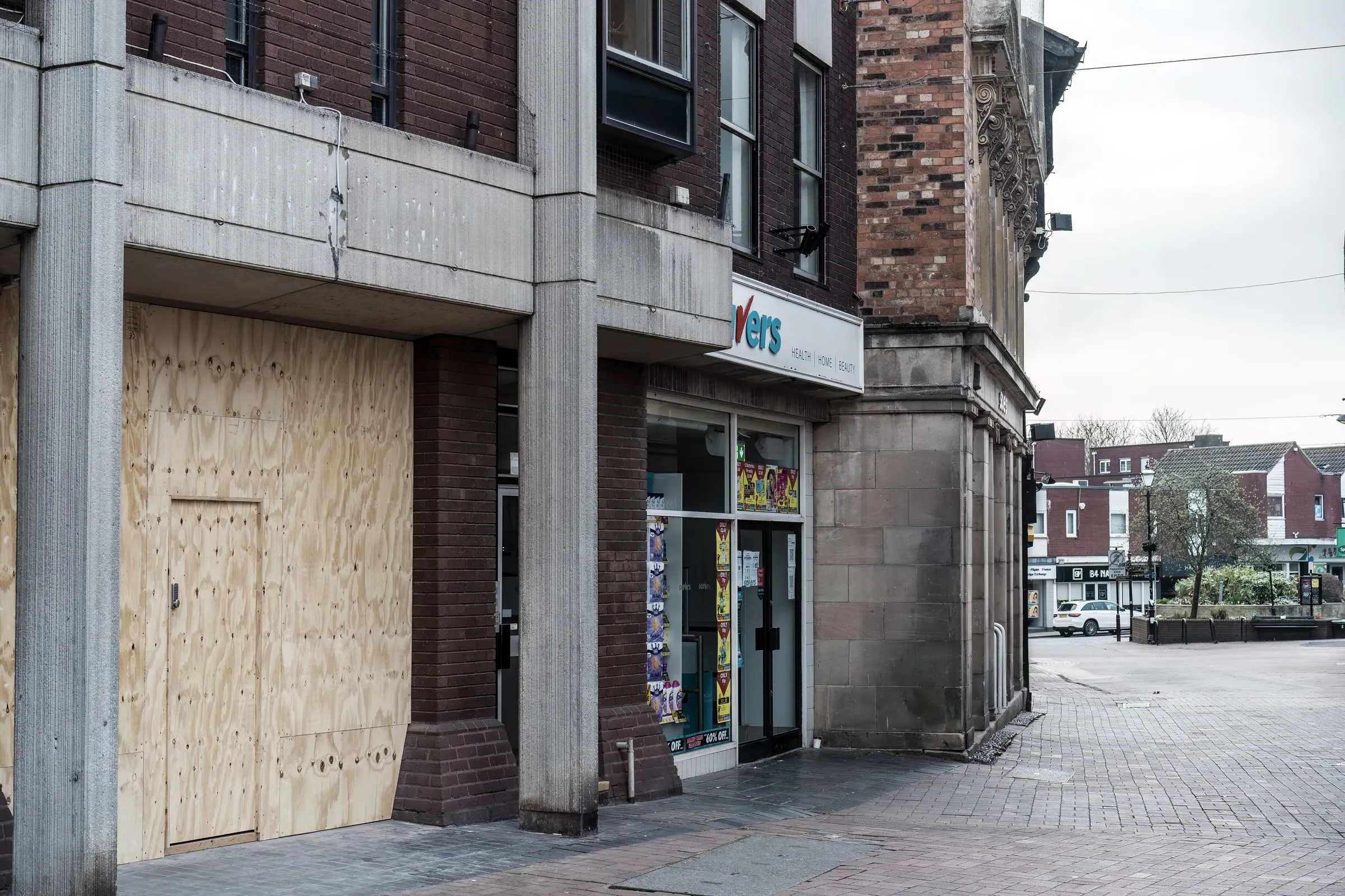 Corner storefront with plywood over the doors and windows on an empty street