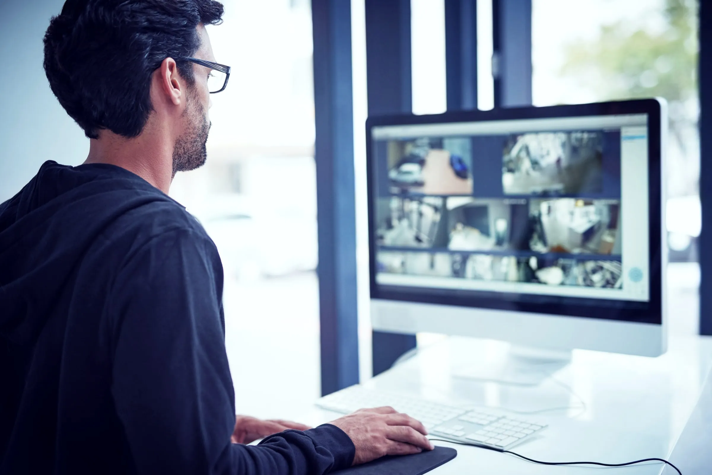 Man at a desk viewing security camera feeds on a monitor