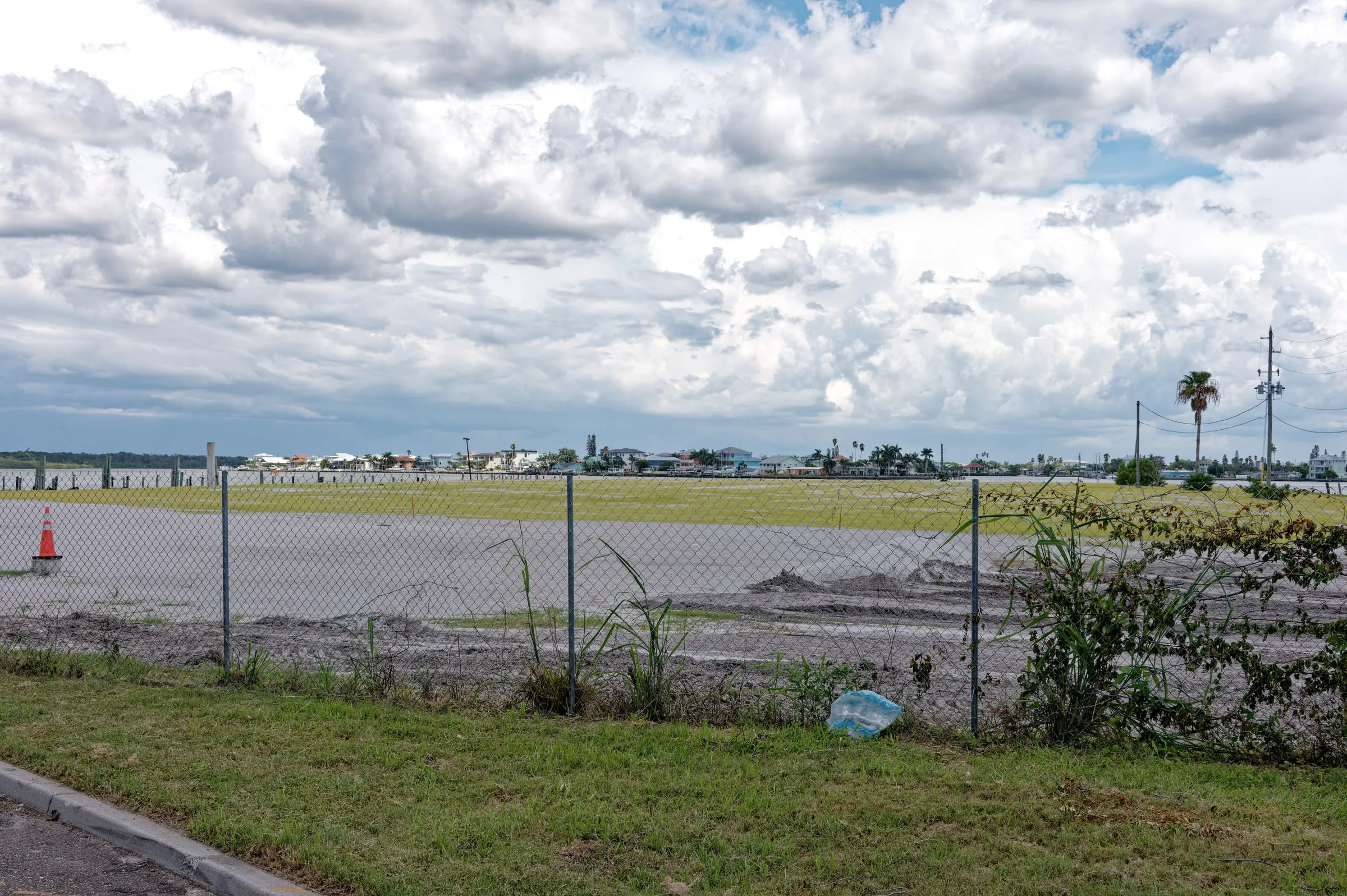 Chain-link fence along a flat, empty tract under a wide cloudy sky