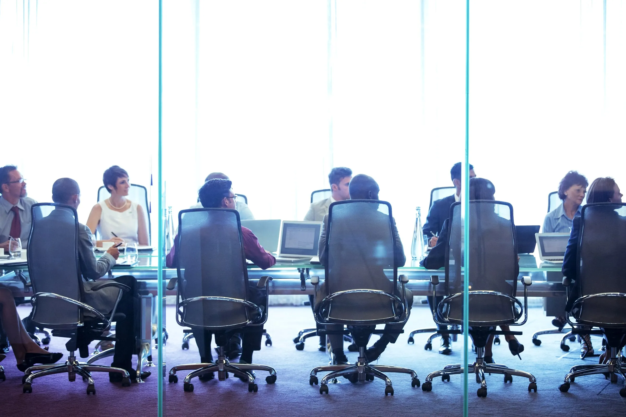 Executives seated around a long conference table in a glass-walled boardroom