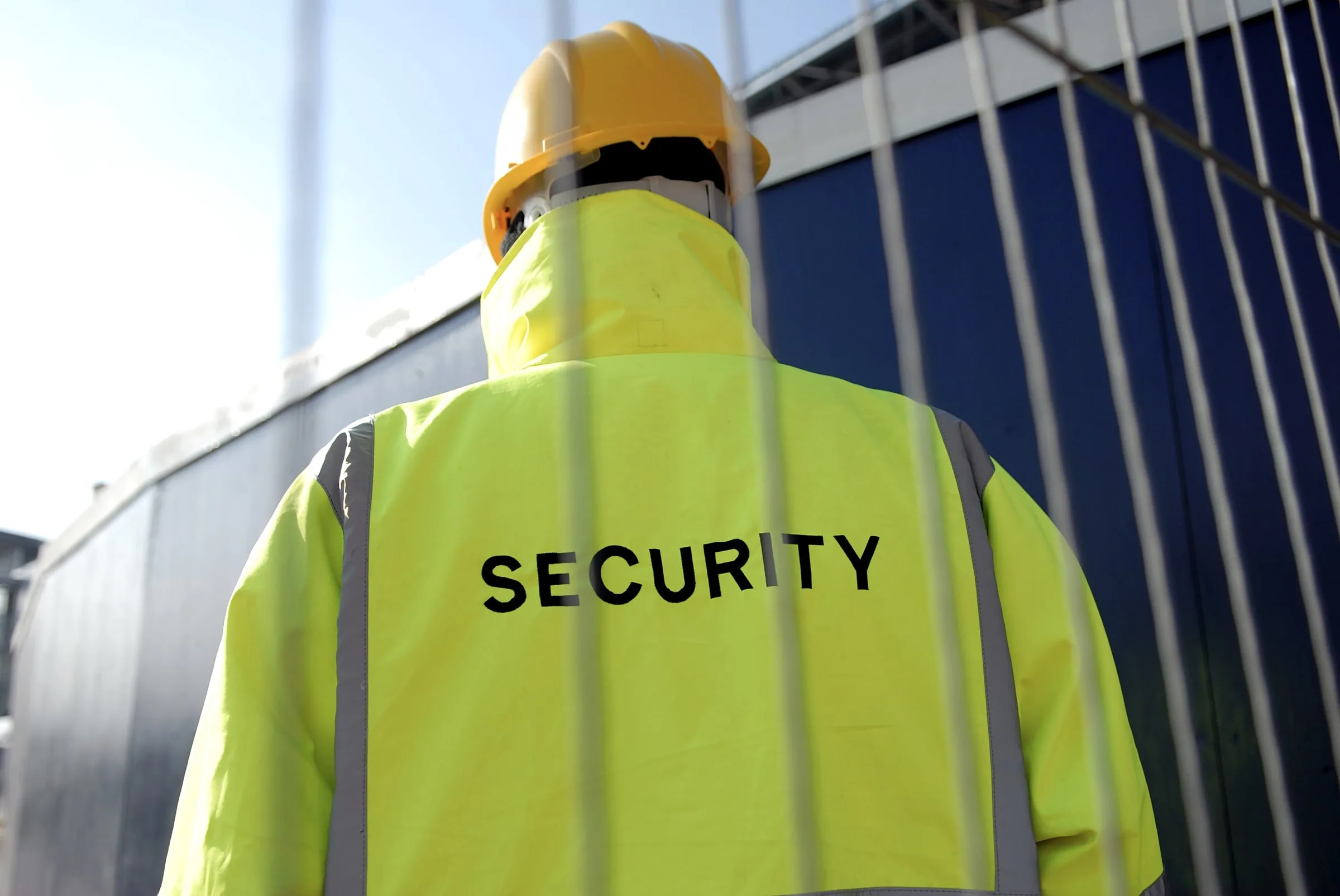 Security officer in a hi-vis jacket at a construction site fence
