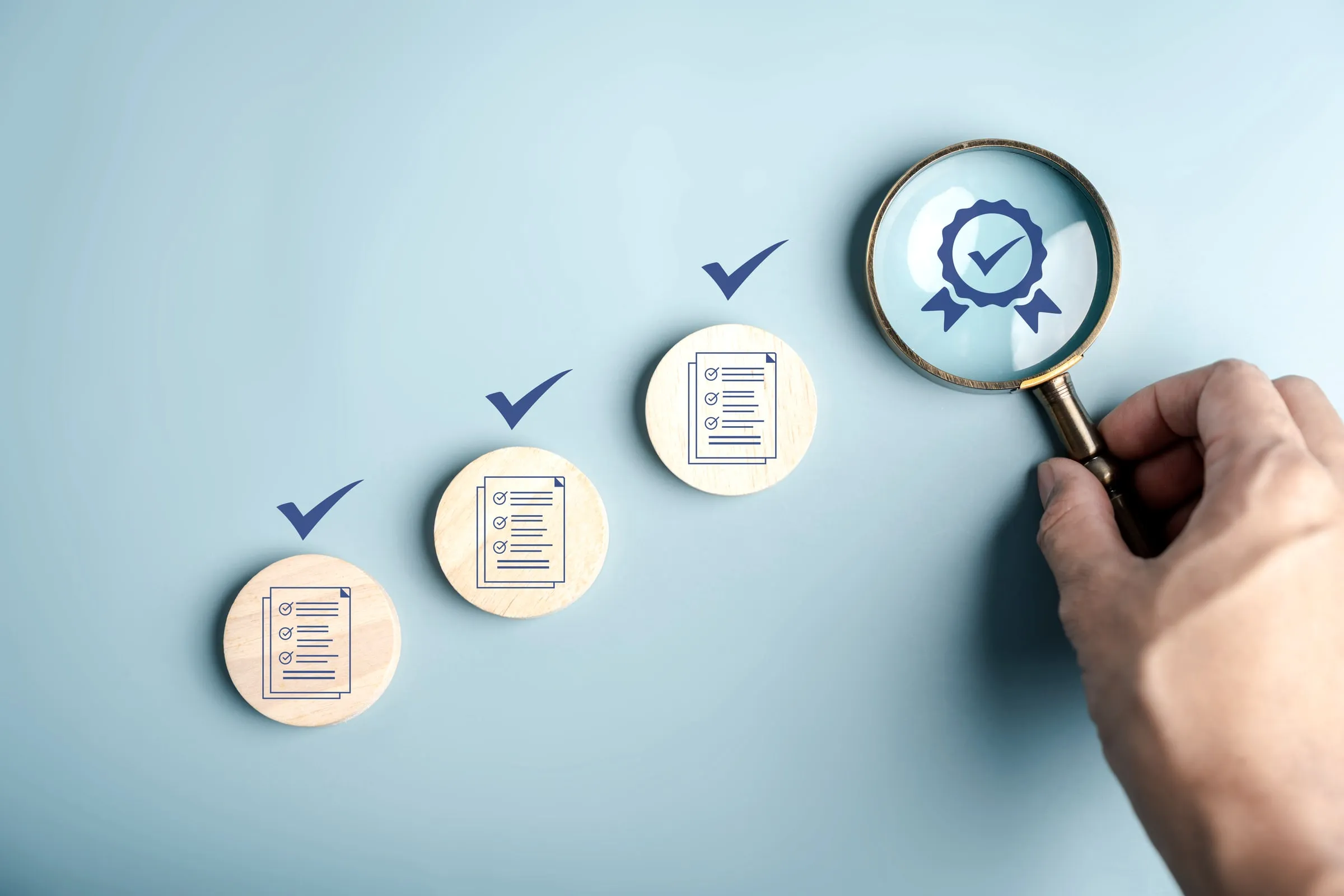 Checklist icons in ascending order beside a magnifying glass held over a certification badge, on a light blue background