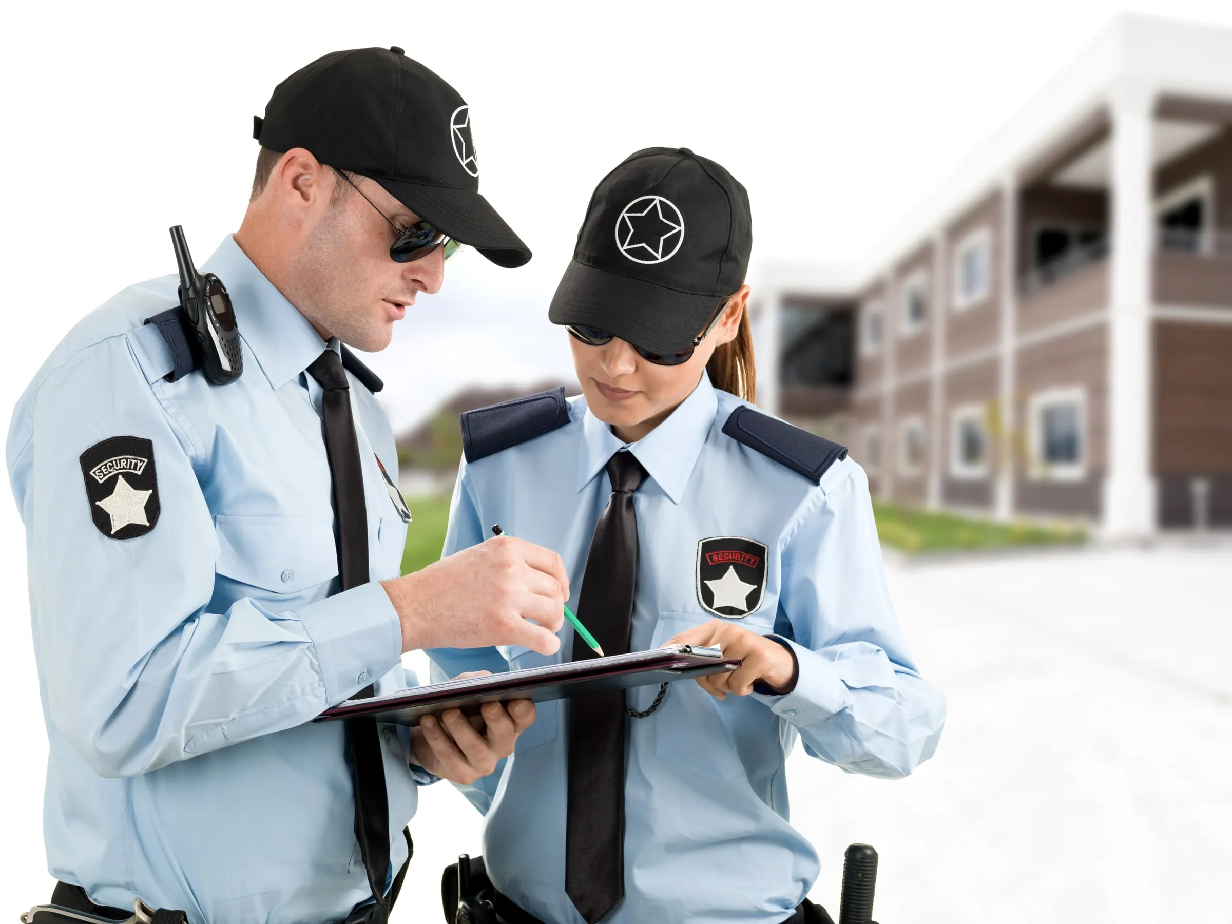 Two uniformed officers in light blue shirts review notes on a clipboard outside an apartment building