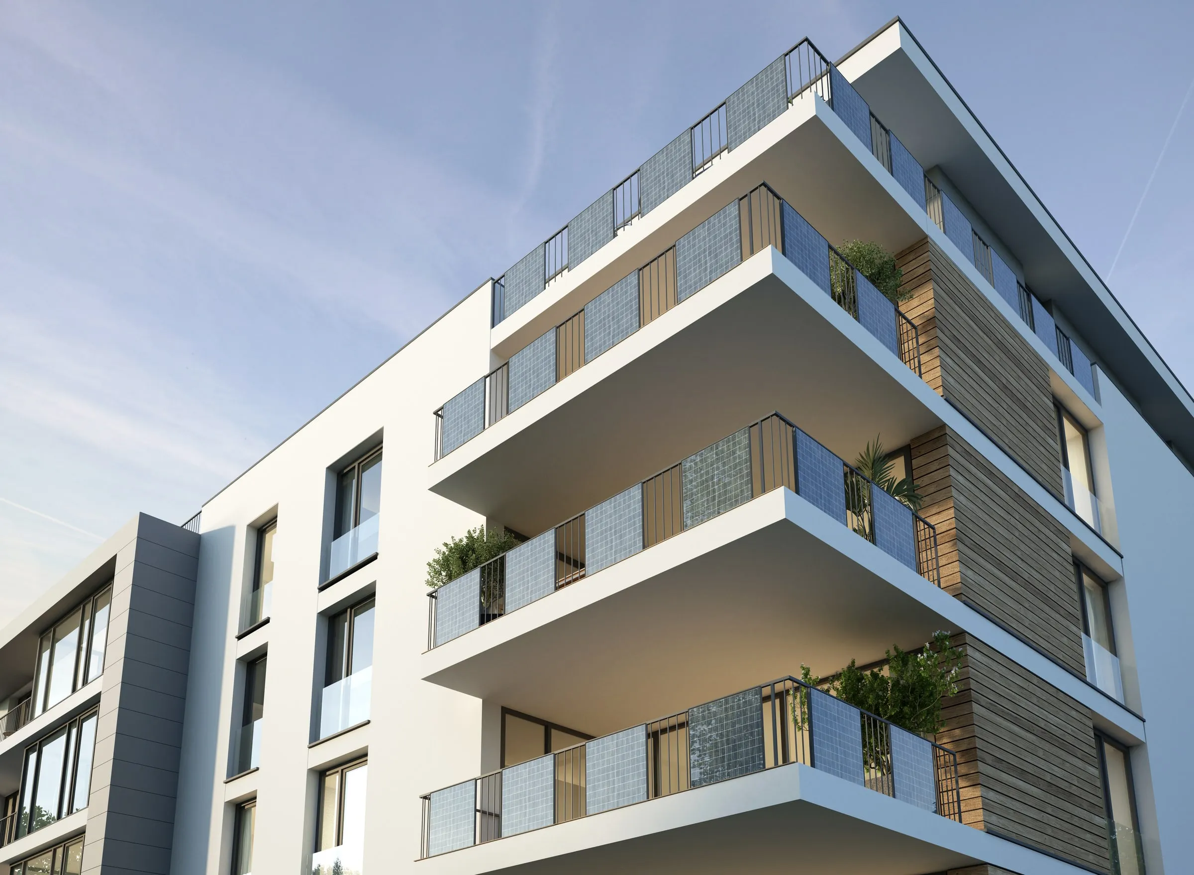 Low-angle view of a modern multi-storey apartment building with balconies and privacy screens against a blue sky