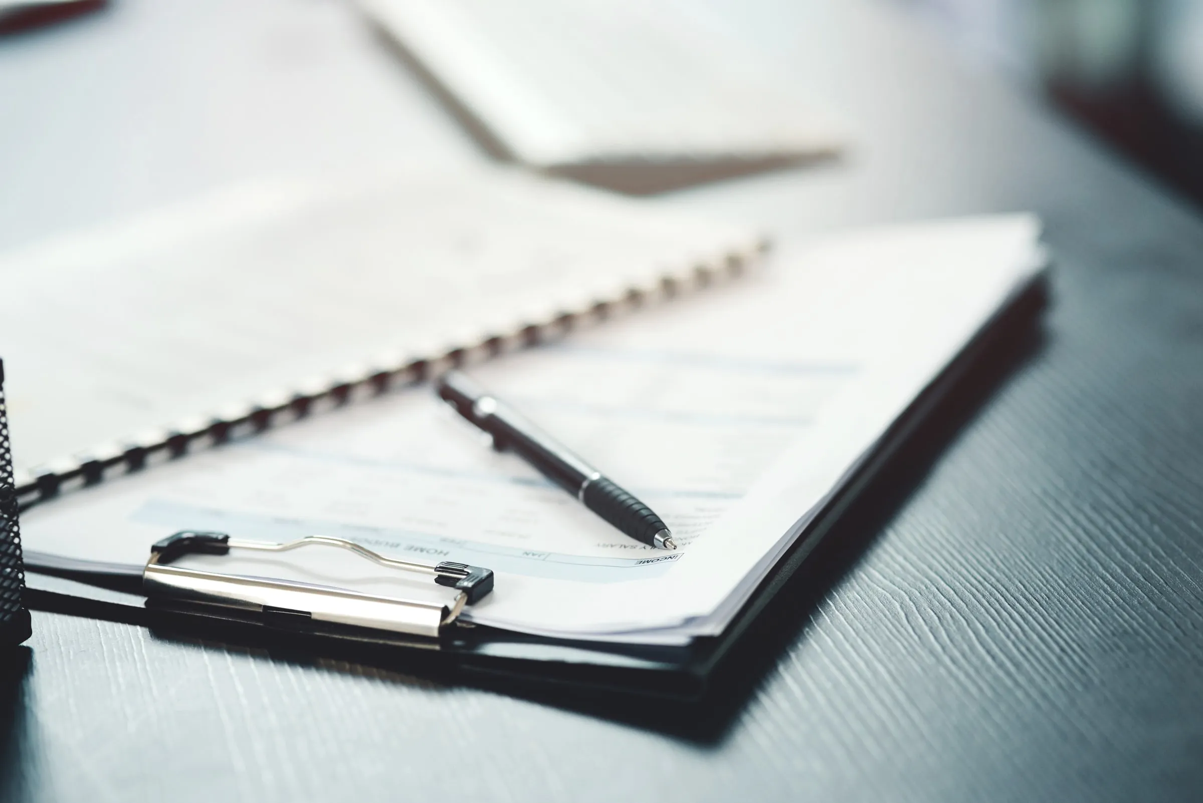Clipboard with printed report pages and a pen resting on a dark desk