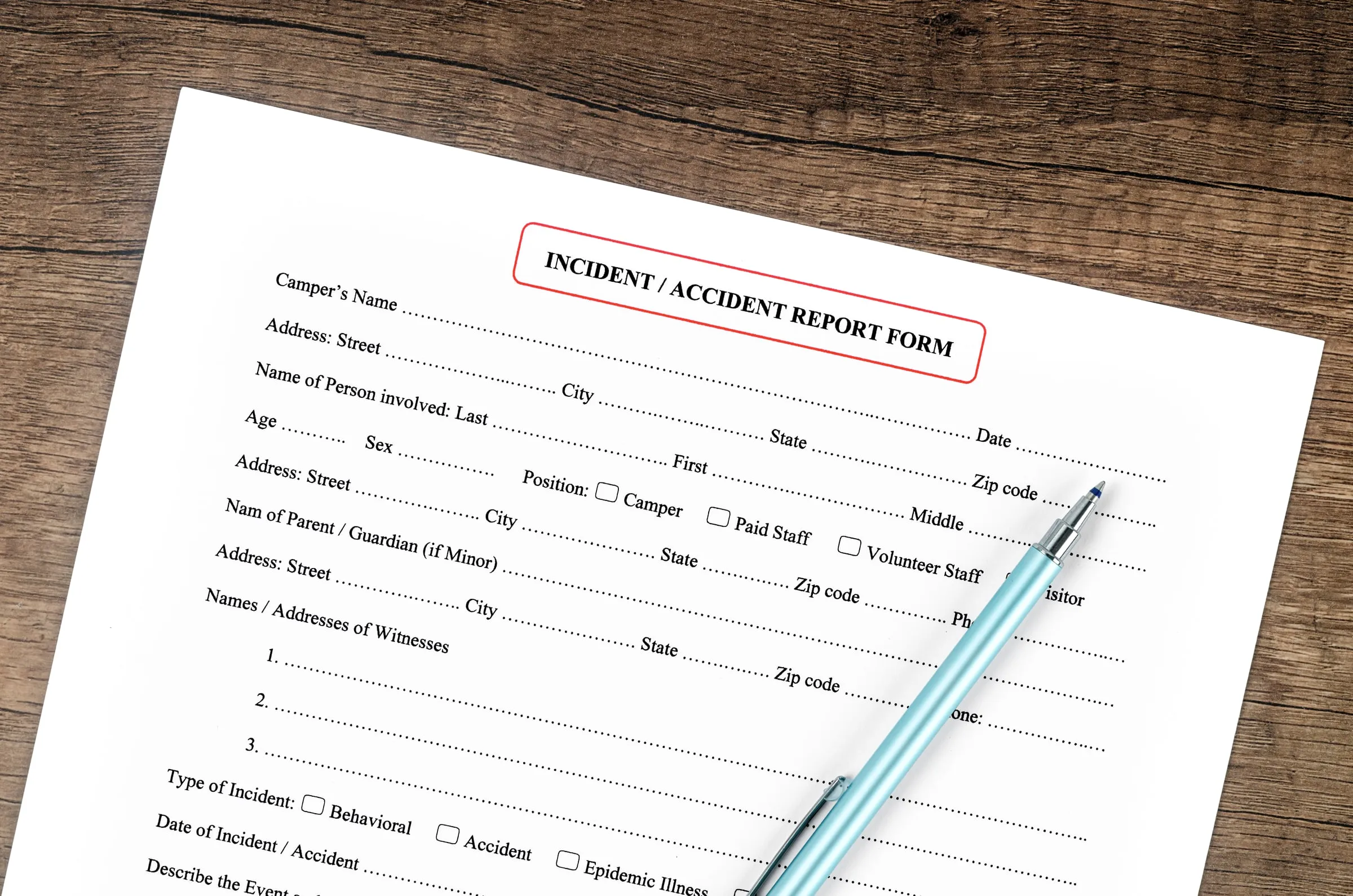 Blank incident and accident report form on a wooden desk with a pen