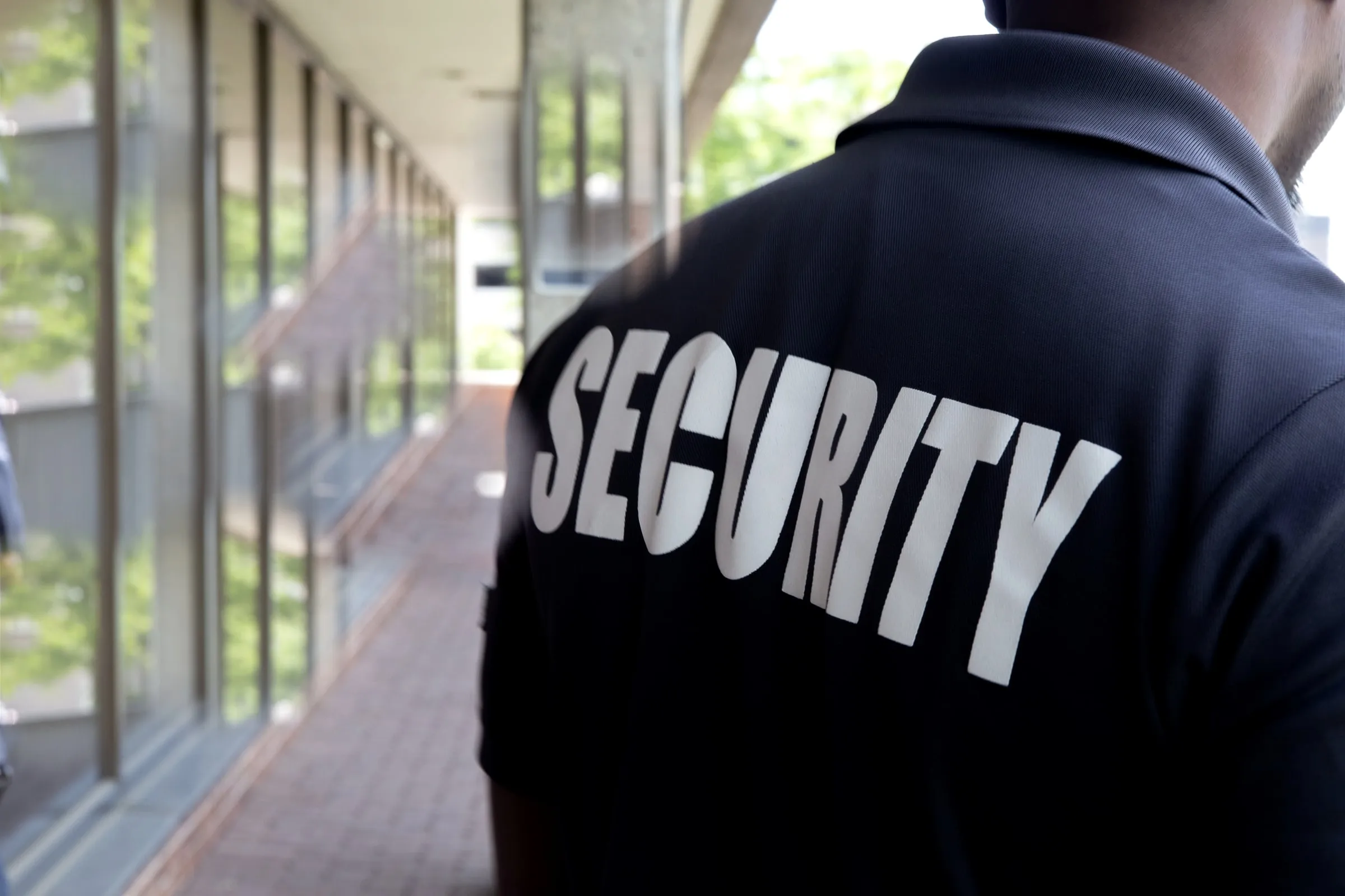 Security officer in a SECURITY shirt watching a downtown Houston street