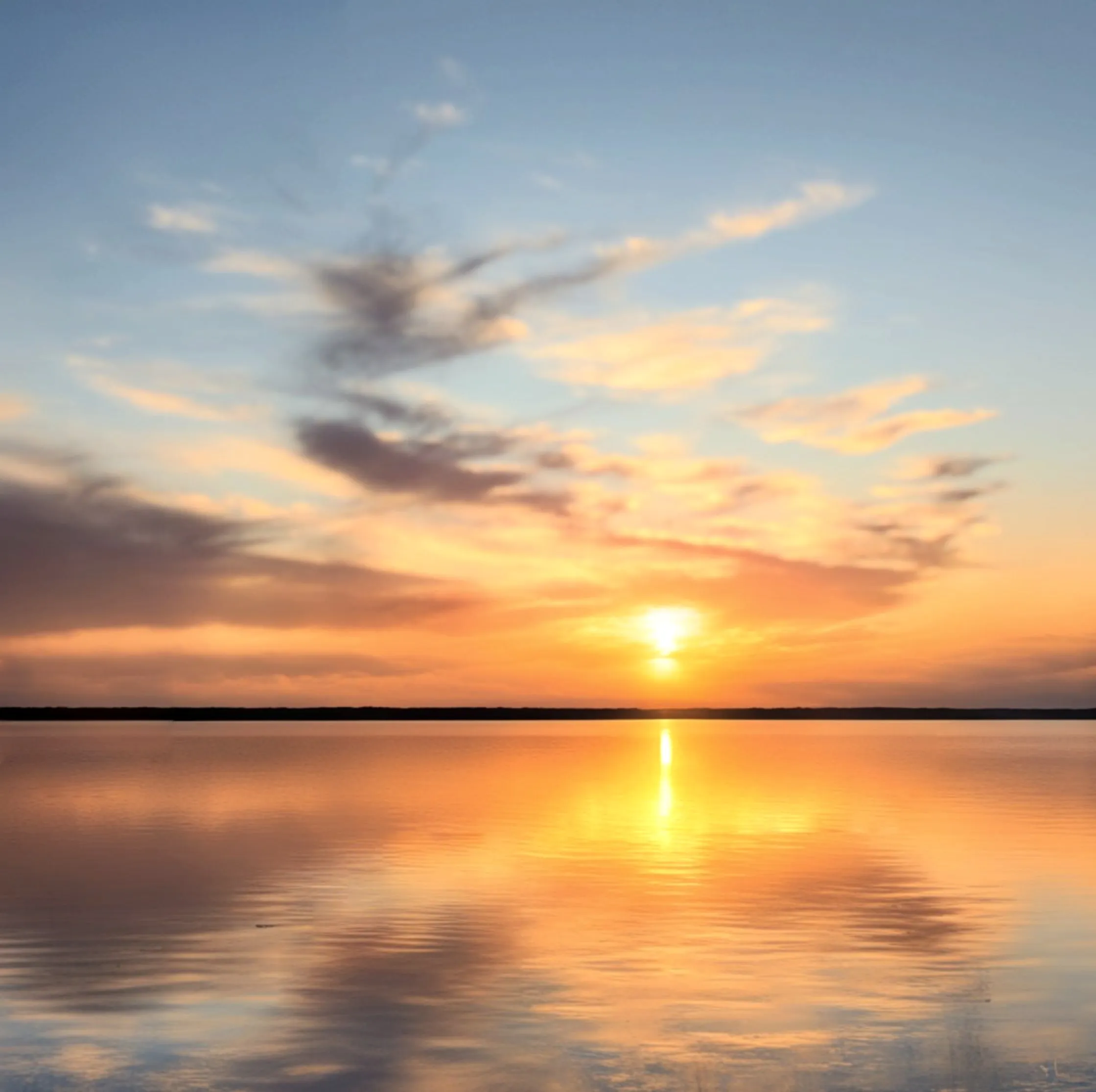 Sunset over a calm lake with the sun reflected in a golden path across the water