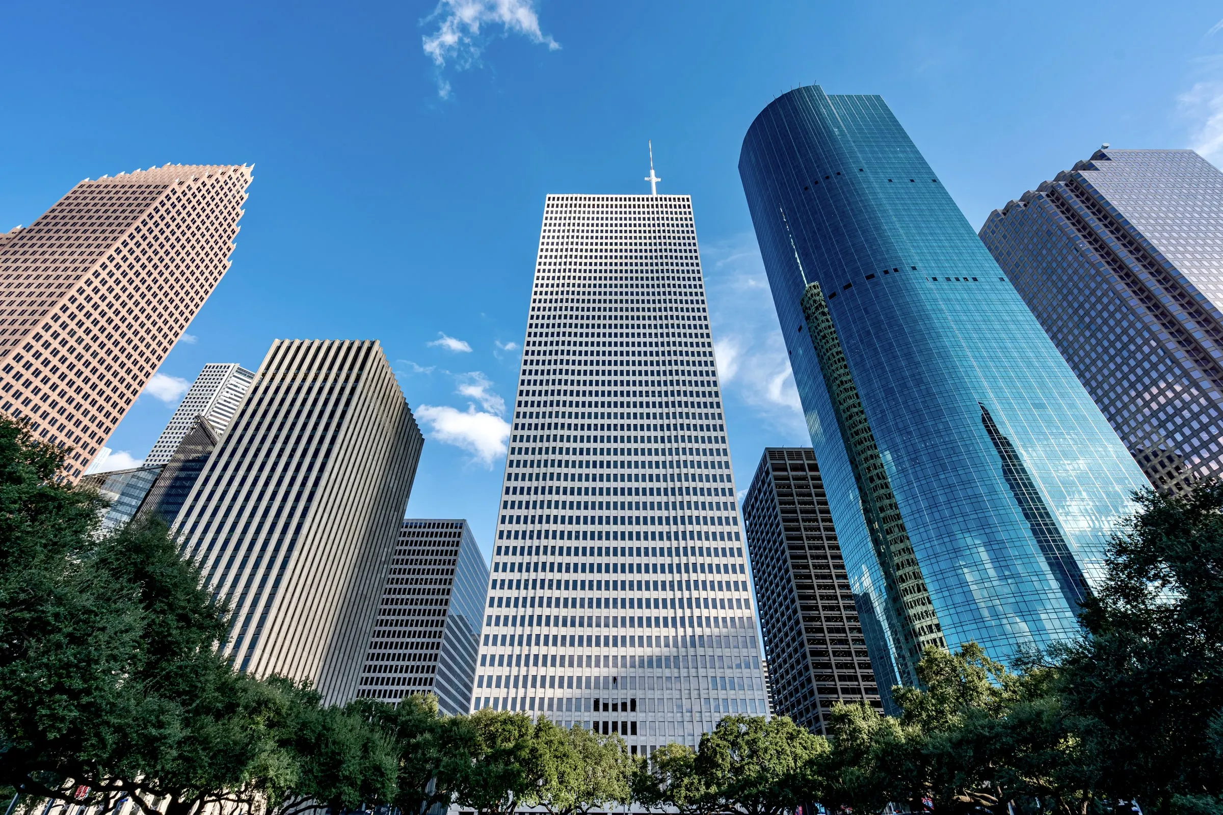 Downtown Houston skyscrapers seen from street level against a clear blue sky