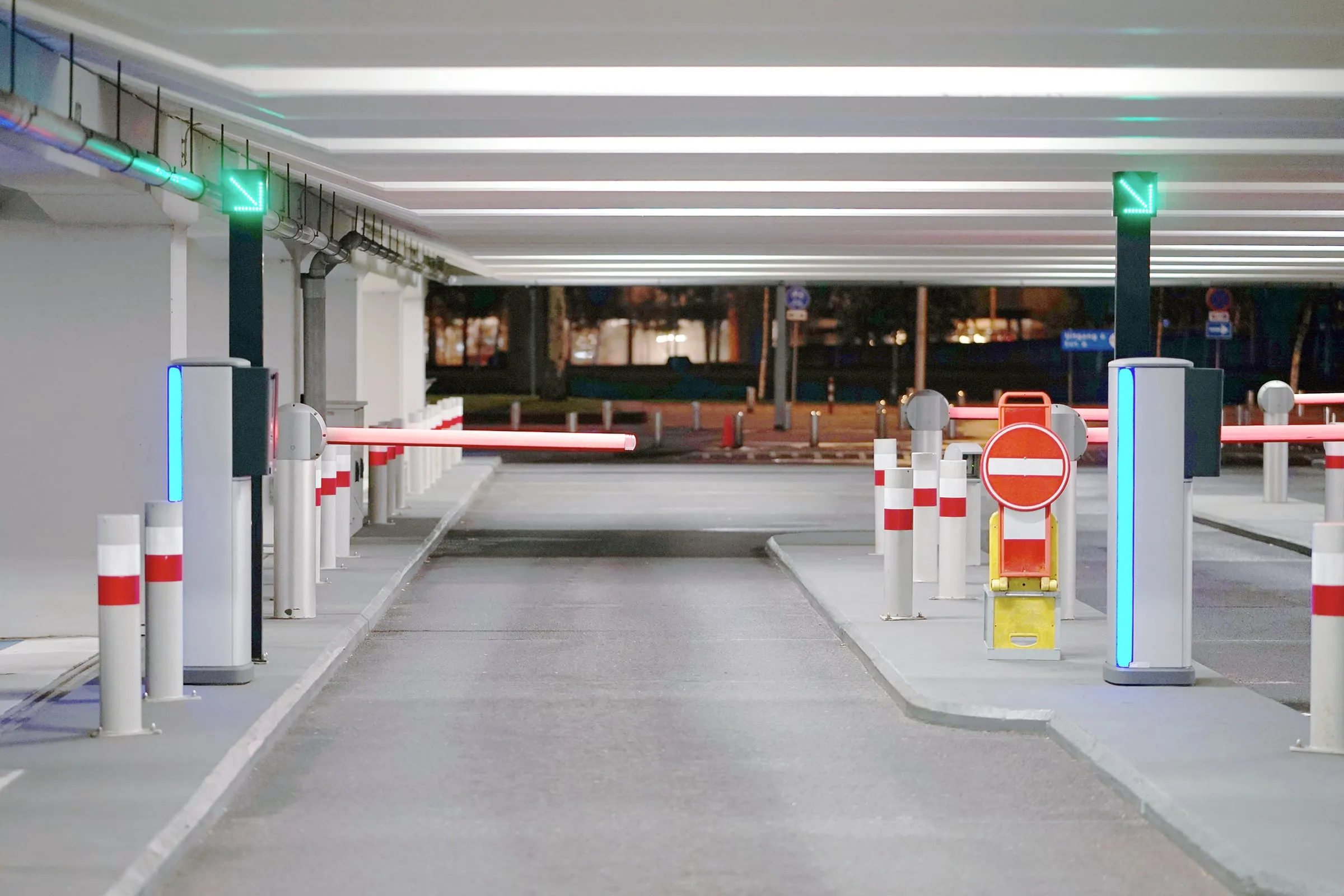 Entrance lanes of a modern parking garage with red-and-white barrier arms and green lane lights
